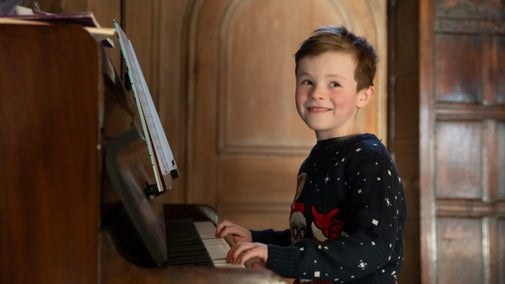 Boy playing piano in Nunnington Hall Oak Hall at Christmas